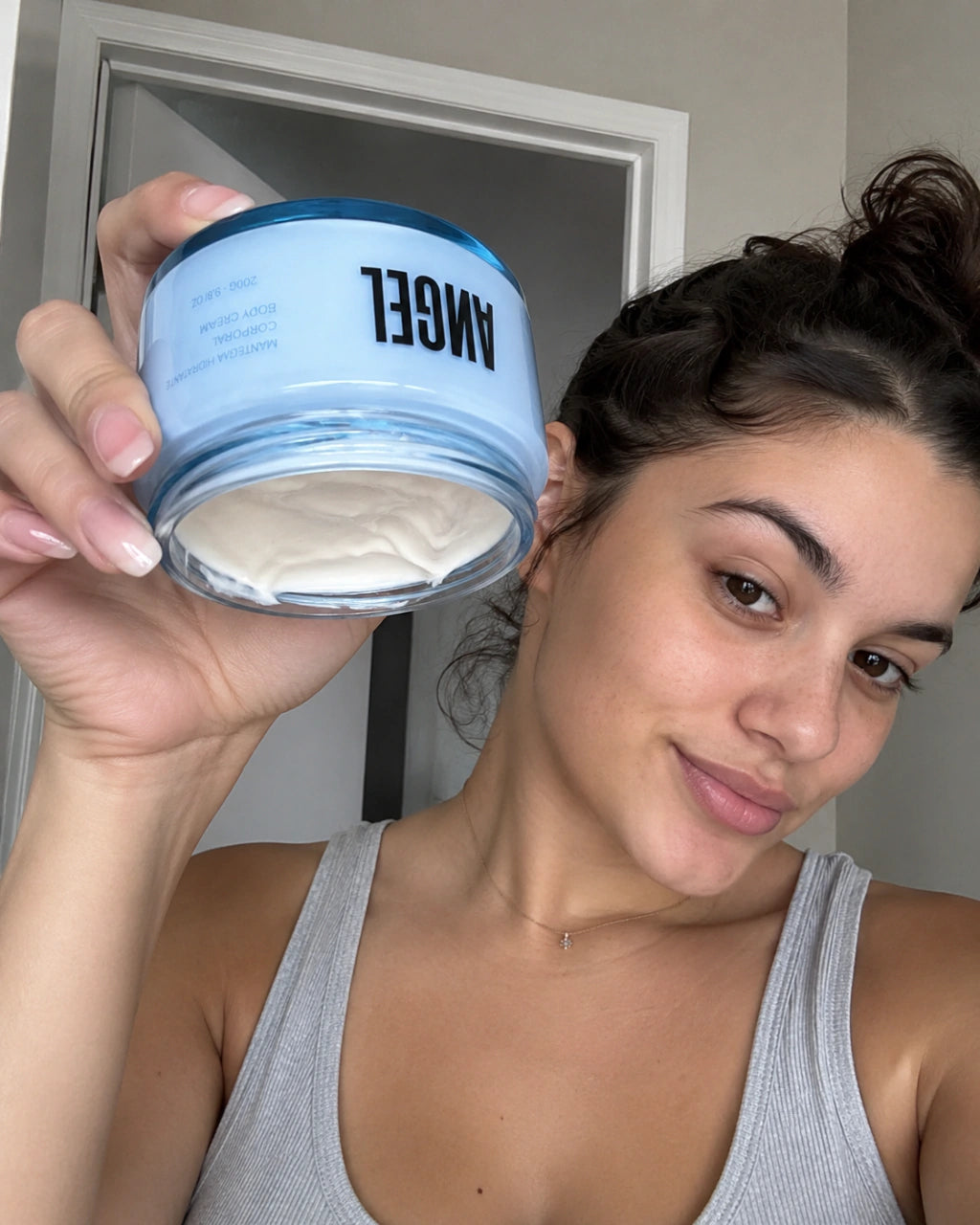 Mulher segurando o pote aberto do bodycream Afeer Of Arabian Angel