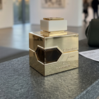Frasco dourado do perfume L'Aventure Femme da Al Haramain em ambiente elegante