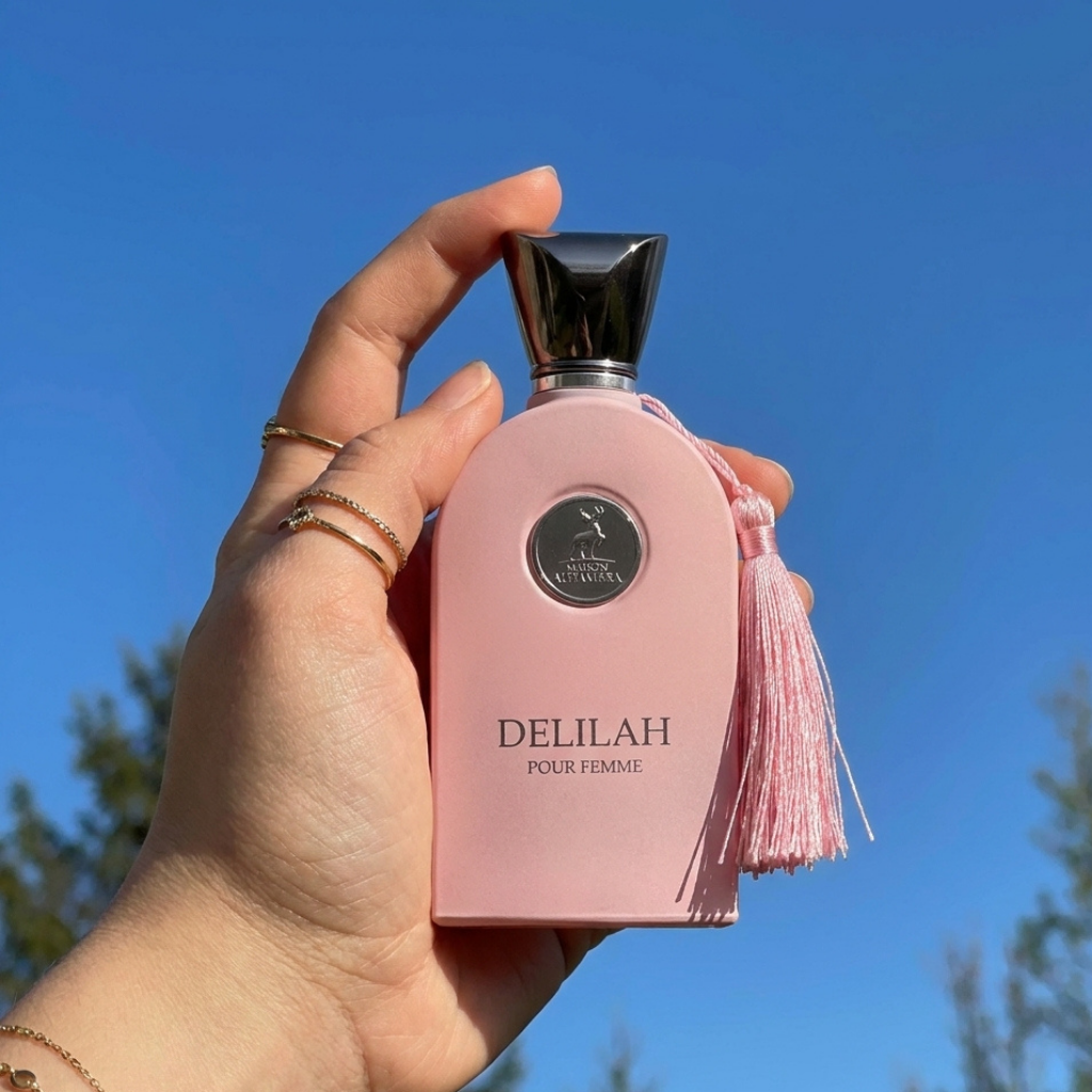 Frasco do perfume Delilah da Maison Alhambra em ambiente externo sob céu azul.