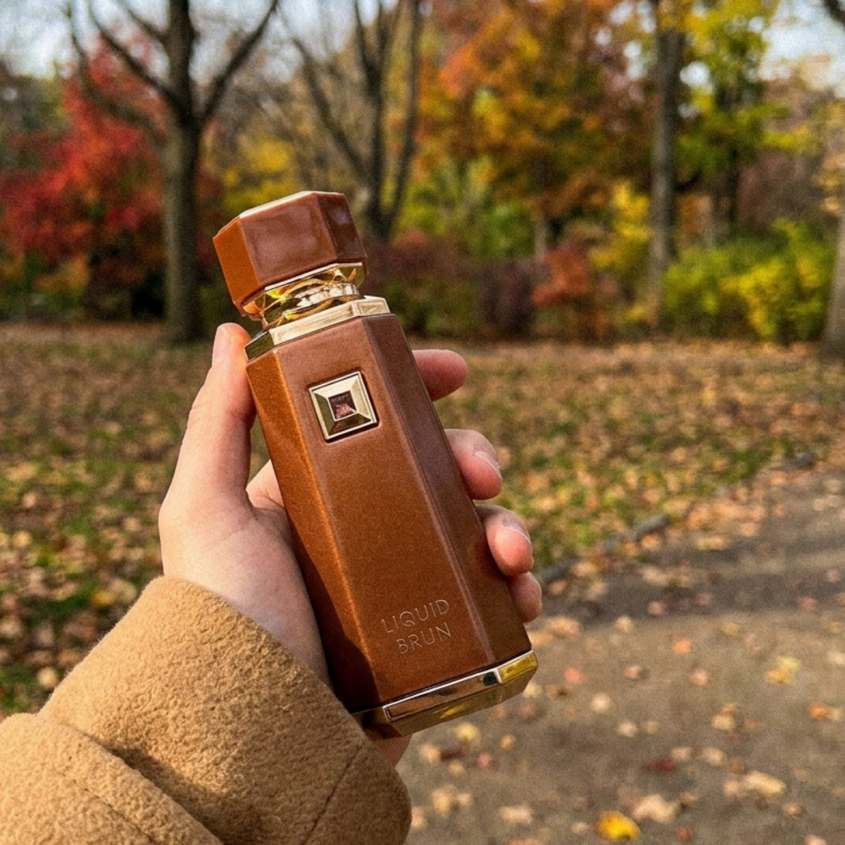 Frasco do perfume French Avenue Liquid Brun em mão em cenário externo de outono