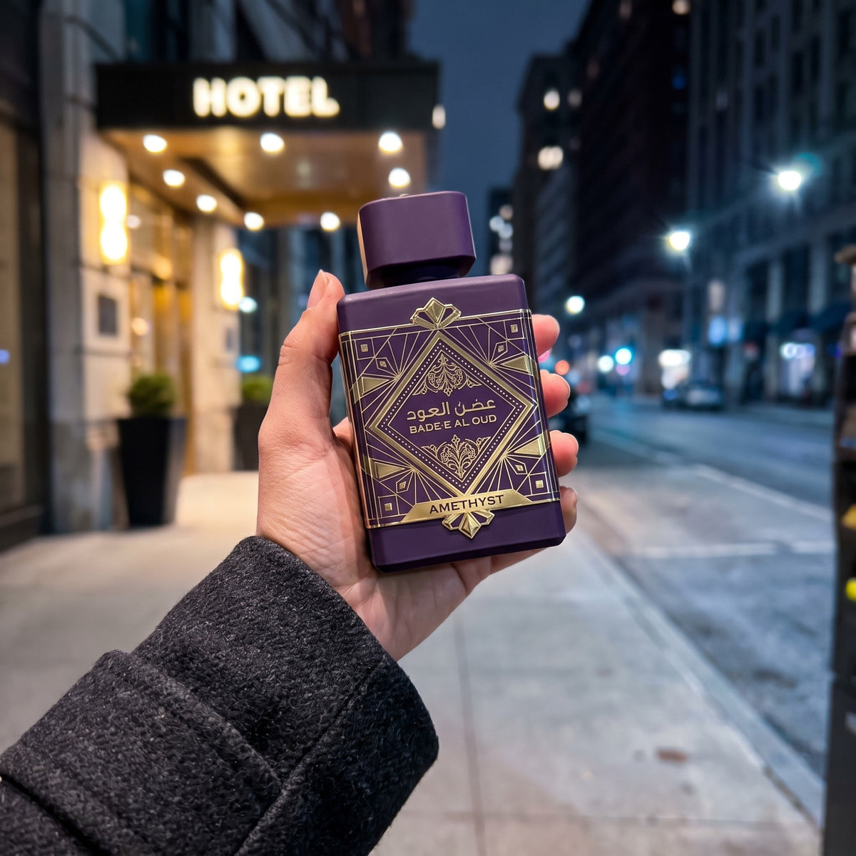 Perfume Lattafa Badee Al Oud Amethyst segurado em ambiente urbano noturno