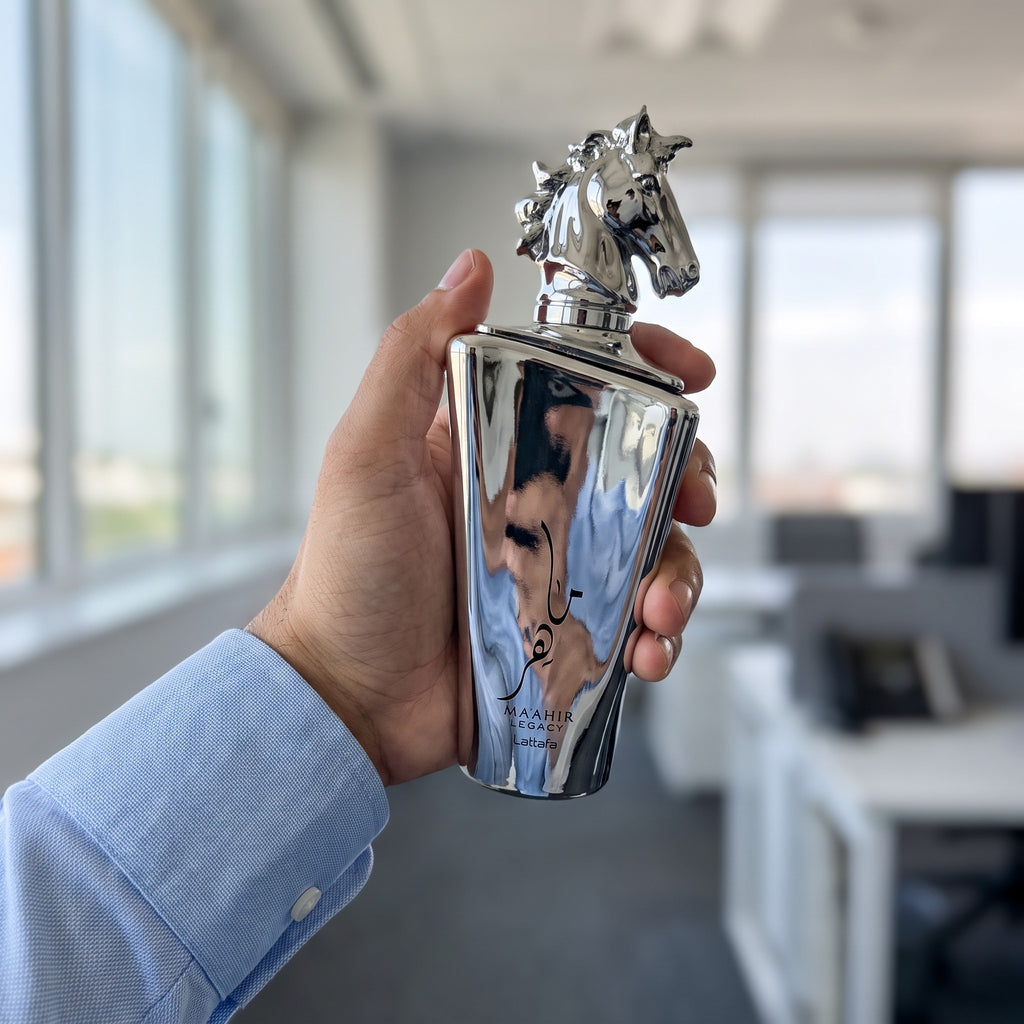 Perfume Lattafa Maahir Legacy segurado em ambiente de trabalho com luz natural