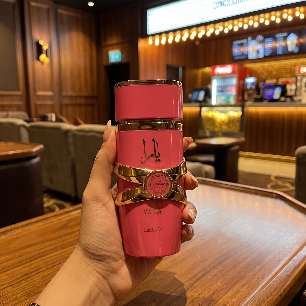 Perfume Lattafa Yara Candy segurado em ambiente de cinema ou lounge com iluminação quente