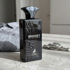 Perfume Maison Alhambra Mindset sobre bancada ao lado de camisa social e relógio