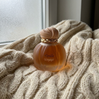 Perfume Maison Asrar Vanilla Voyage sobre manta de tricô em ambiente aconchegante
