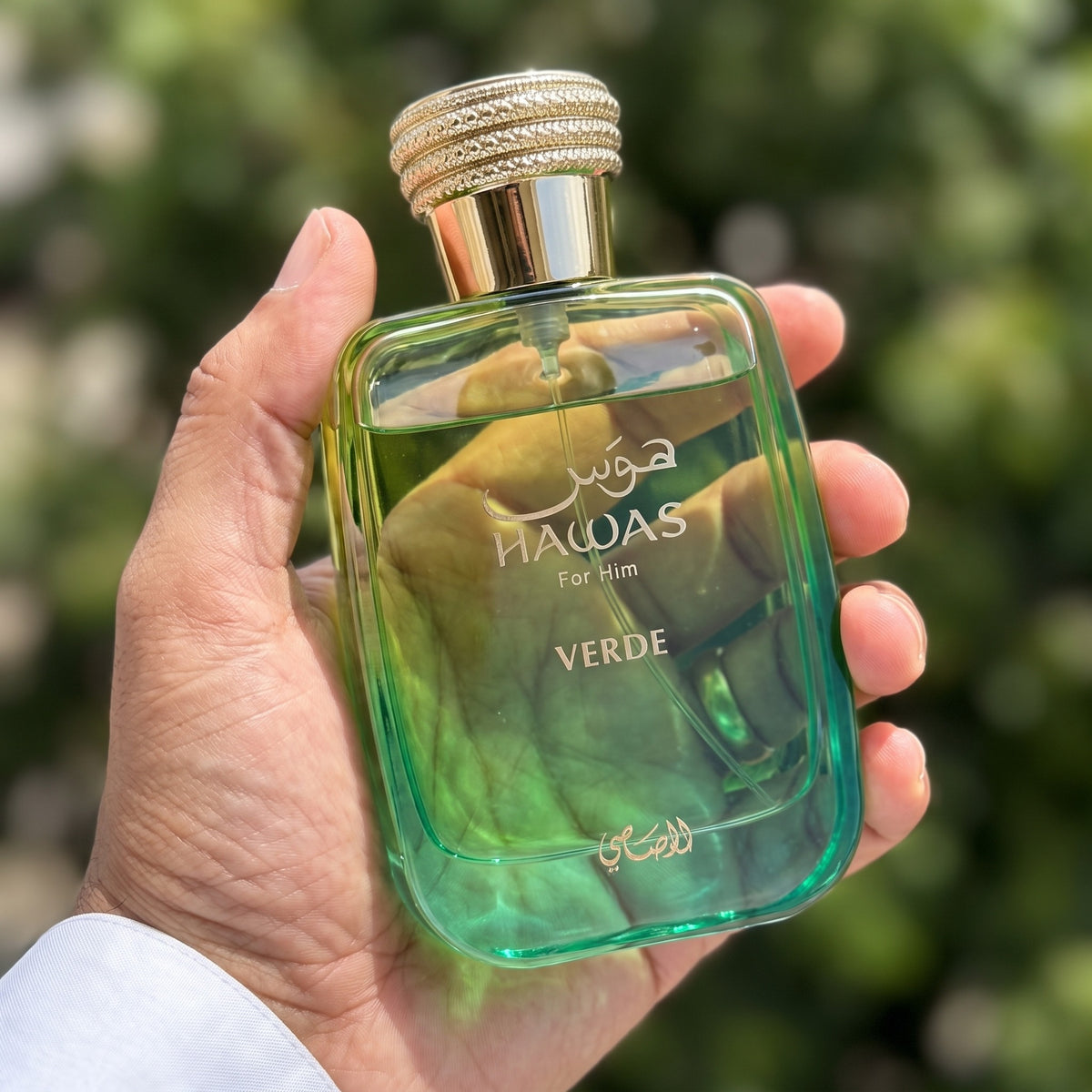 Perfume Rasasi Hawas Verde segurado em ambiente externo ensolarado